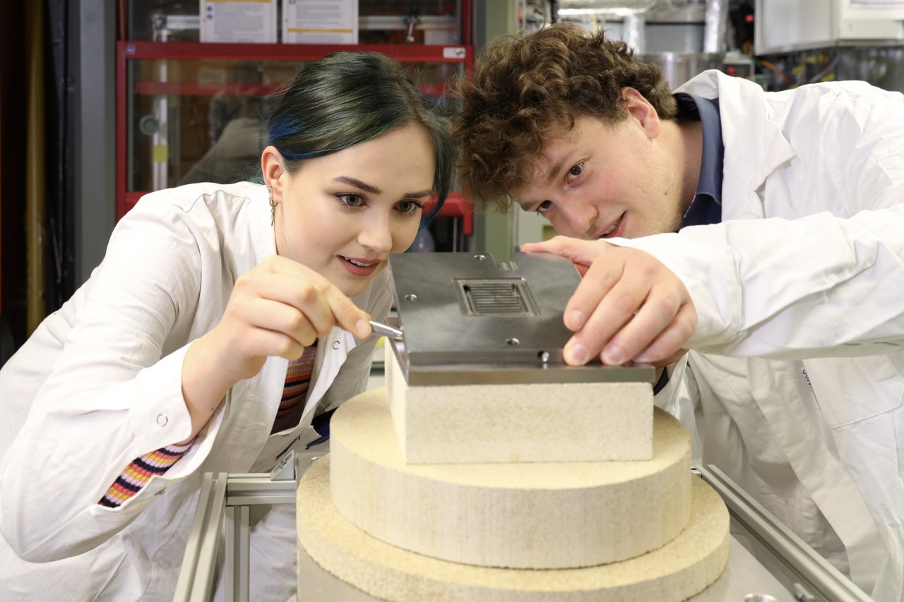 Zwei Studierende arbeiten in einem Labor zusammen an einer Vorrichtung 
