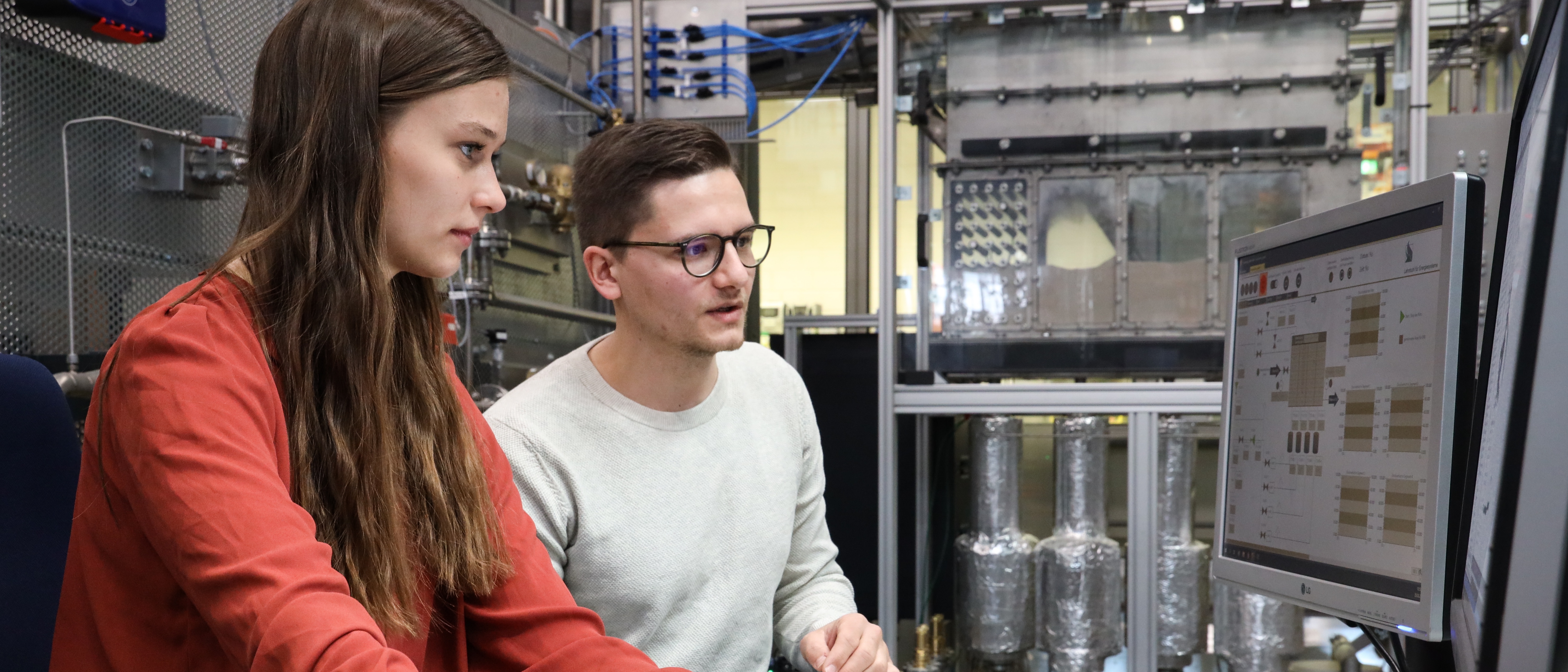 Zwei Studenten sitzen vor einem Computerbildschirm, auf dem ein Simulationsprogramm läuft